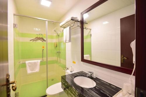 a bathroom with a sink and a shower with a mirror at BOOK PAVILION HOTEL in Dongguan