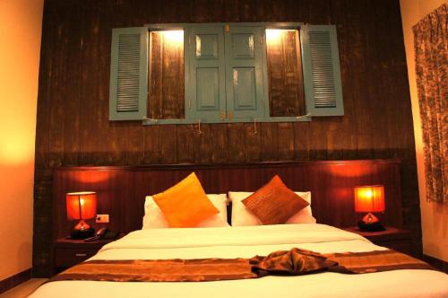 a bedroom with a bed with two lamps and a window at King Hotel in Ban Tha Phae