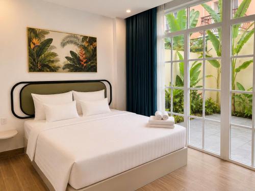 a bedroom with a white bed and a large window at Blue Hotel Sunset Town Phu Quoc in Phú Quốc