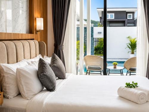 a bedroom with a white bed and a large window at The Phuview Pool Villa Aonang in Ban Chong Phli
