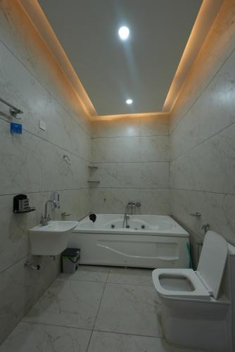 a bathroom with a tub and a toilet and a sink at hotel baromas retreat in Jawālāpur