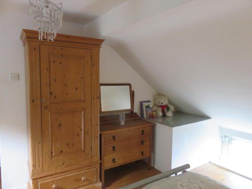 a bedroom with a wooden dresser and a mirror at The Coach House Self Catering Apartments in Glenariff