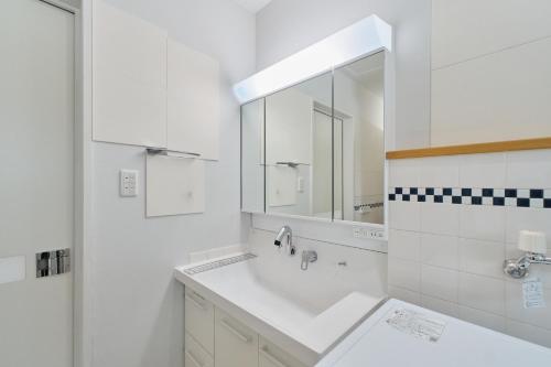 a white bathroom with a sink and a mirror at Suzuran Haus in Higashikawa