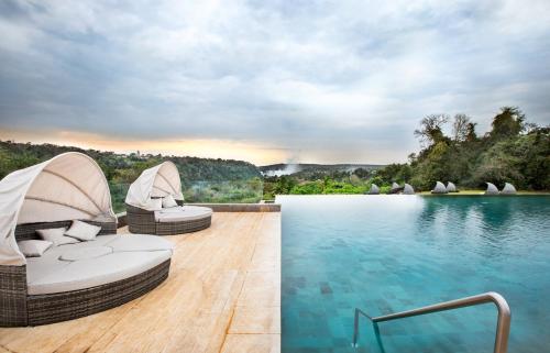 a swimming pool with two lounge chairs next to the water at Gran Meliá Iguazú in Puerto Iguazú