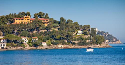 a boat in the water with houses on a hill at Albergo Filippo II in Porto Santo Stefano