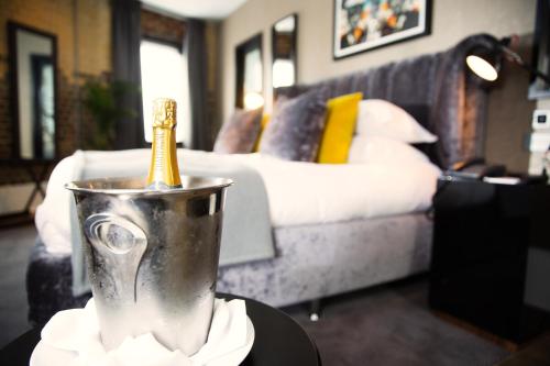 a silver bucket with a bottle in it with a bed at Malmaison Oxford in Oxford