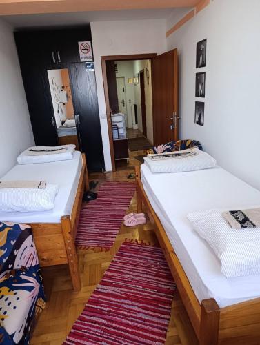 two beds in a room with two rugs at Agape in Niš