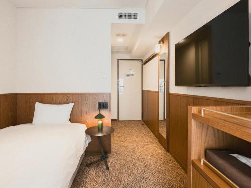 a hotel room with a bed and a flat screen tv at WPÜ HOTEL Shinjuku in Tokyo
