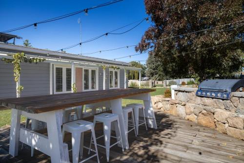 a large white table and stools in front of a house at Edelweiss Cottage in Berridale