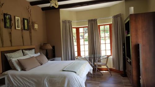 a bedroom with a bed and a table and windows at Tuckaway in Somerset West