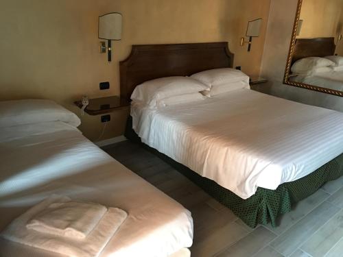 two beds in a hotel room with a mirror at Hotel Don Carlo in Broni
