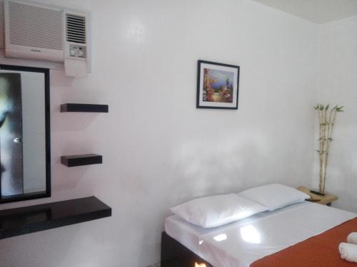 a white room with a bed and a tv at Dahilig Resort in Puerto Galera