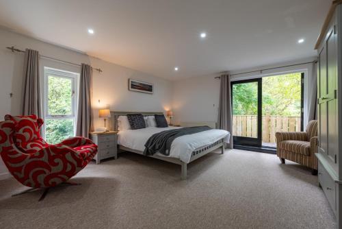 a bedroom with a bed and a chair and a window at Warner - Treworgie Barton Cottages in Bude