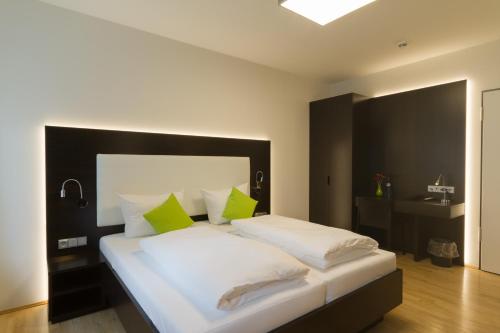 a bedroom with a large white bed with green pillows at sevenDays Hotel BoardingHouse Mannheim in Mannheim