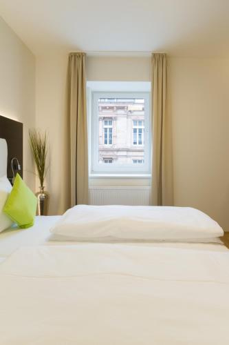 a white bed in a room with a window at sevenDays Hotel BoardingHouse Mannheim in Mannheim