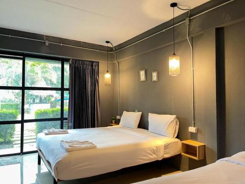 a bedroom with two beds and a large window at Warehouse18 Pool Cafe Resort in Don Sak