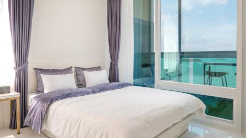 a bedroom with a bed and a large window at Yeosu Hemiswi SPA Pension in Yeosu