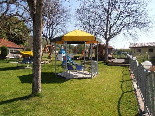 a park with a playground with a yellow umbrella at Ferienanlage Seehof in Krumpendorf am Wörthersee
