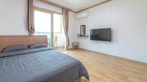 a bedroom with a bed and a flat screen tv at Samcheok Greenhyang Pension in Samcheok