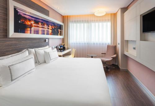 a hotel room with a large bed and a television at Meliá Lebreros in Seville