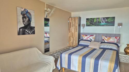 a bedroom with a bed and a couch in it at VACANCES PAISIBLES - Option Menu & petit-déjeuners payant in Saint-Paul