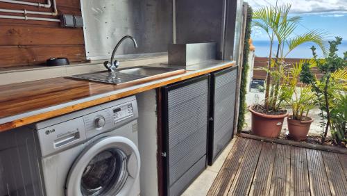 an outdoor kitchen with a washing machine on a deck at VACANCES PAISIBLES - Option Menu & petit-déjeuners payant in Saint-Paul