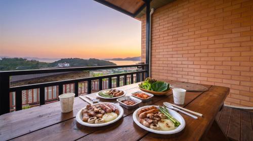 a wooden table with plates of food on a balcony at Yeosu Hwangto Pension in Yeosu