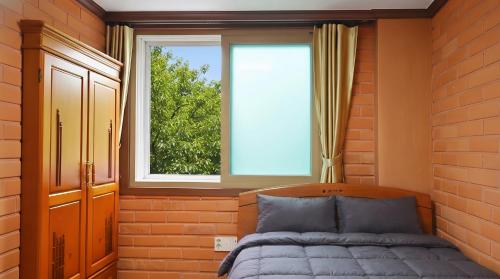 a bedroom with a bed and a window at Yeosu Hwangto Pension in Yeosu