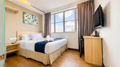 a hotel room with a bed and a flat screen tv at Orange Hotel Kota Kemuning @ Shah Alam in Shah Alam
