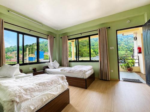 a bedroom with two beds and large windows at Niru Yoga Homestay sound healing & hiking retreat in Bhaktapur