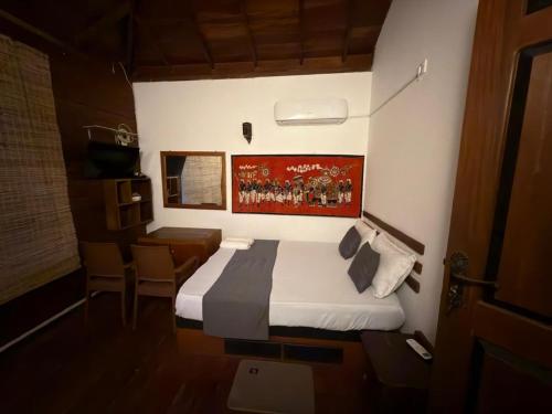 a bedroom with a bed and a painting on the wall at Luck Uyana Cabana Pinnawala in Pinnawala