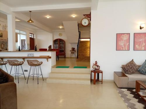 a kitchen and living room with a counter and stools at Skye in Hortons in Pattipola