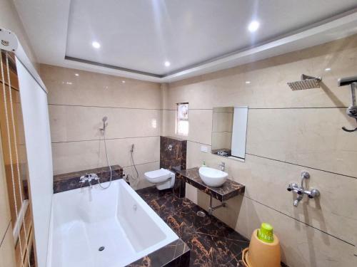 a bathroom with a tub and a toilet and a sink at Sangam Hotel in Kiul