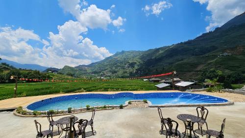 a swimming pool with chairs and mountains in the background at Stilla Home in Tả Van