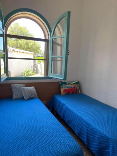 two beds sitting in a room with a window at Villino Sicaru' in Simius