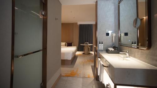 a bathroom with a sink and a bed in a room at Elong Hotel Jakarta PIK in Jakarta
