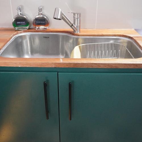 a stainless steel sink in a kitchen with green cabinets at Pequeño Refugio in Ticul