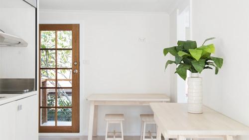 a white kitchen with a table and a vase with a plant at Whalesong in New Brighton