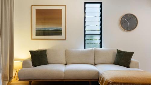a living room with a couch and a clock on the wall at Brunswick Palms 1 in Brunswick Heads