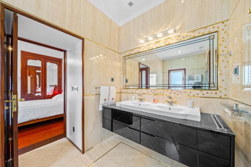 a bathroom with a sink and a large mirror at Quinta da Paz in Caniço