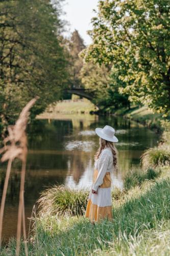 a young girl in a hat standing by a river at Liva Park Nature Resort in Liwa