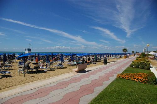 a beach with chairs and umbrellas and the ocean at Hotel Germania in Lido di Jesolo