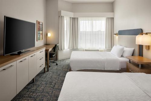 a hotel room with two beds and a flat screen tv at Homewood Suites New Brighton in Roseville