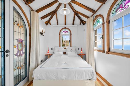 a bedroom with a bed in a room with windows at Quinta da Paz in Caniço