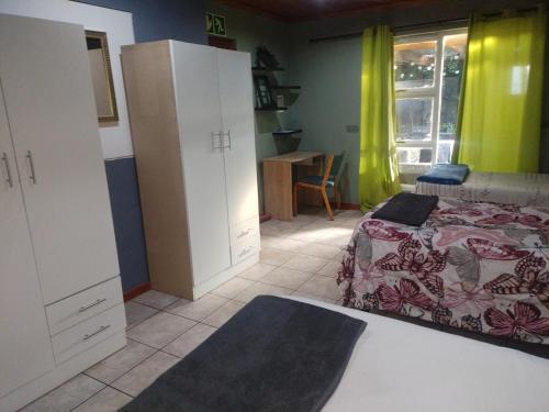a bedroom with a bed and cabinets and a window at Vee's Cottage in Bellville