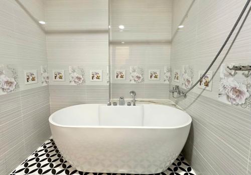 a white tub in a bathroom with flowers on the wall at Phu Gia Hotel 13-15 Hoàng Quốc Việt in Ho Chi Minh City