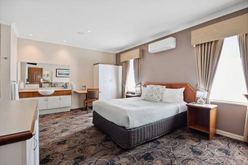 a hotel room with a bed and a bathroom at Quality Hotel Bayswater in Perth