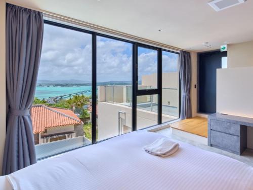 a bedroom with a large bed and a large window at Kandor Resort Okinawa in Nakijin