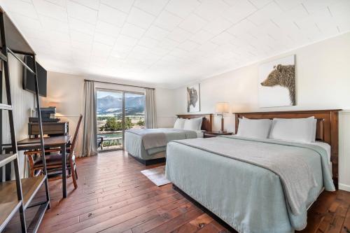 a hotel room with two beds and a desk at Yellowstone Valley Lodge, an Ascend Collection Hotel in Pray