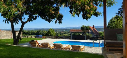a swimming pool in a yard with chairs around it at Vila Daško in Lukavac